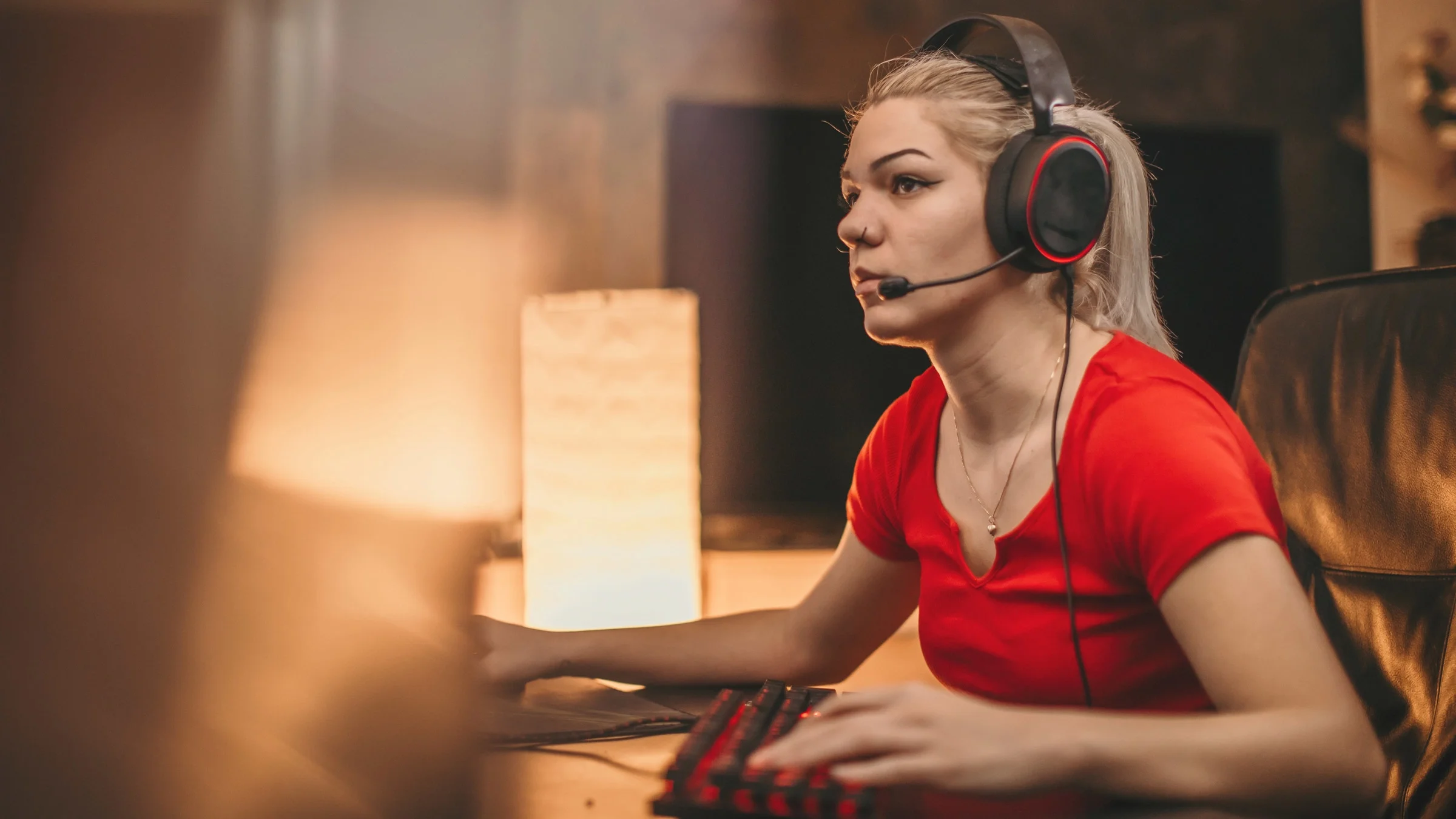 Young woman with gaming headphones on immersed in her computer game.