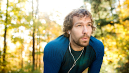 A man wearing headphones takes a break during a run outside.
Halfpoint/iStock via Getty Images Plus 