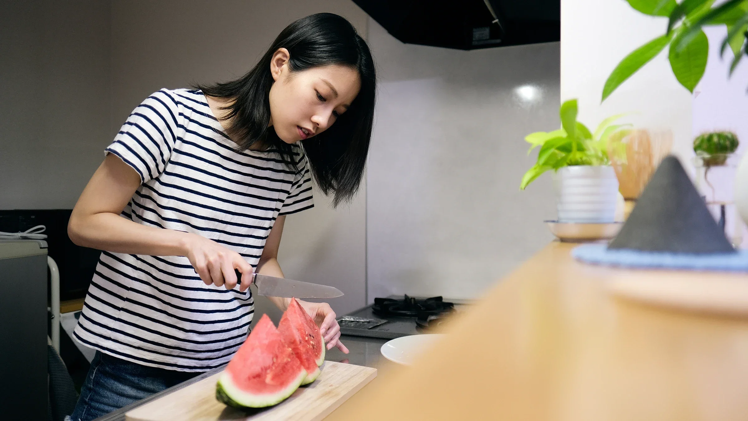 A woman is shown cutting watermelon in a kitchen.
monzenmachi/iStock via Getty Images Plus 