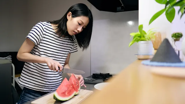 Menstrual pain: woman cutting watermelon 1417806629