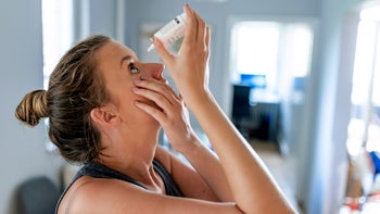 Health: young woman using eye drops 1158023095