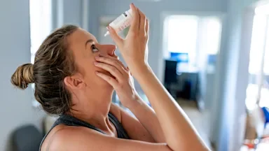 Young woman using eye drops.
ljubaphoto/iStock via Getty Images
