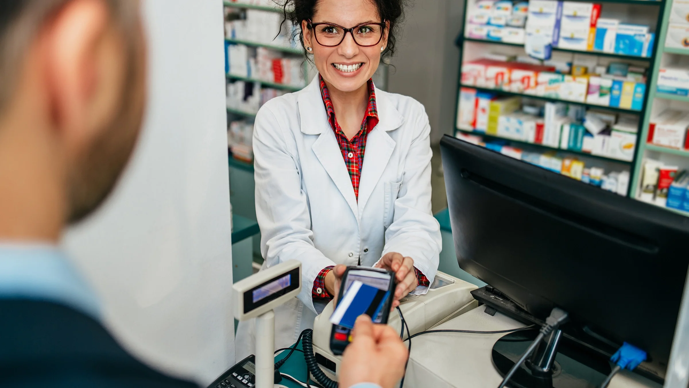 Man paying for medication at pharmacy counter.