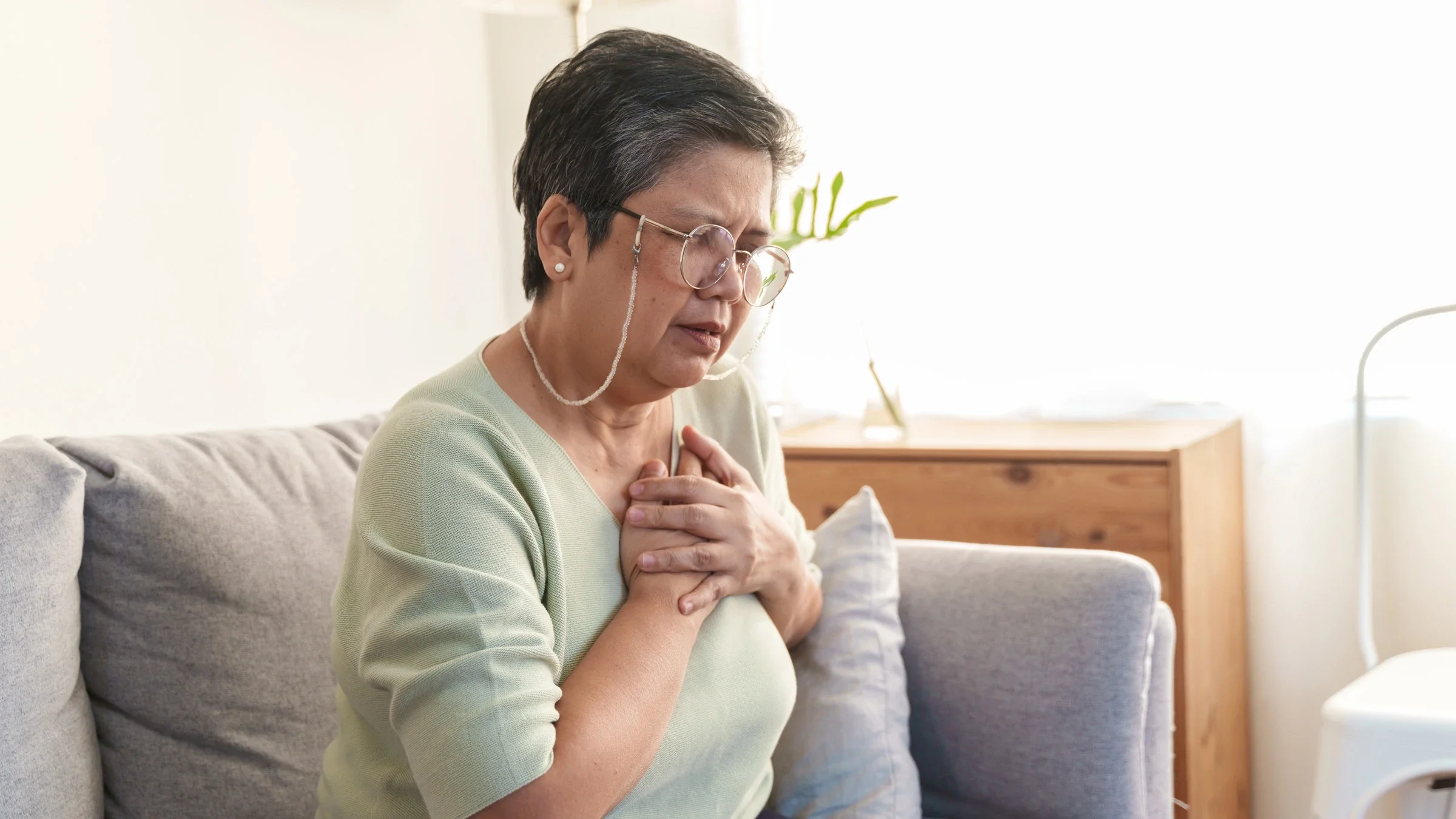 A person experiencing chest pain on their couch.