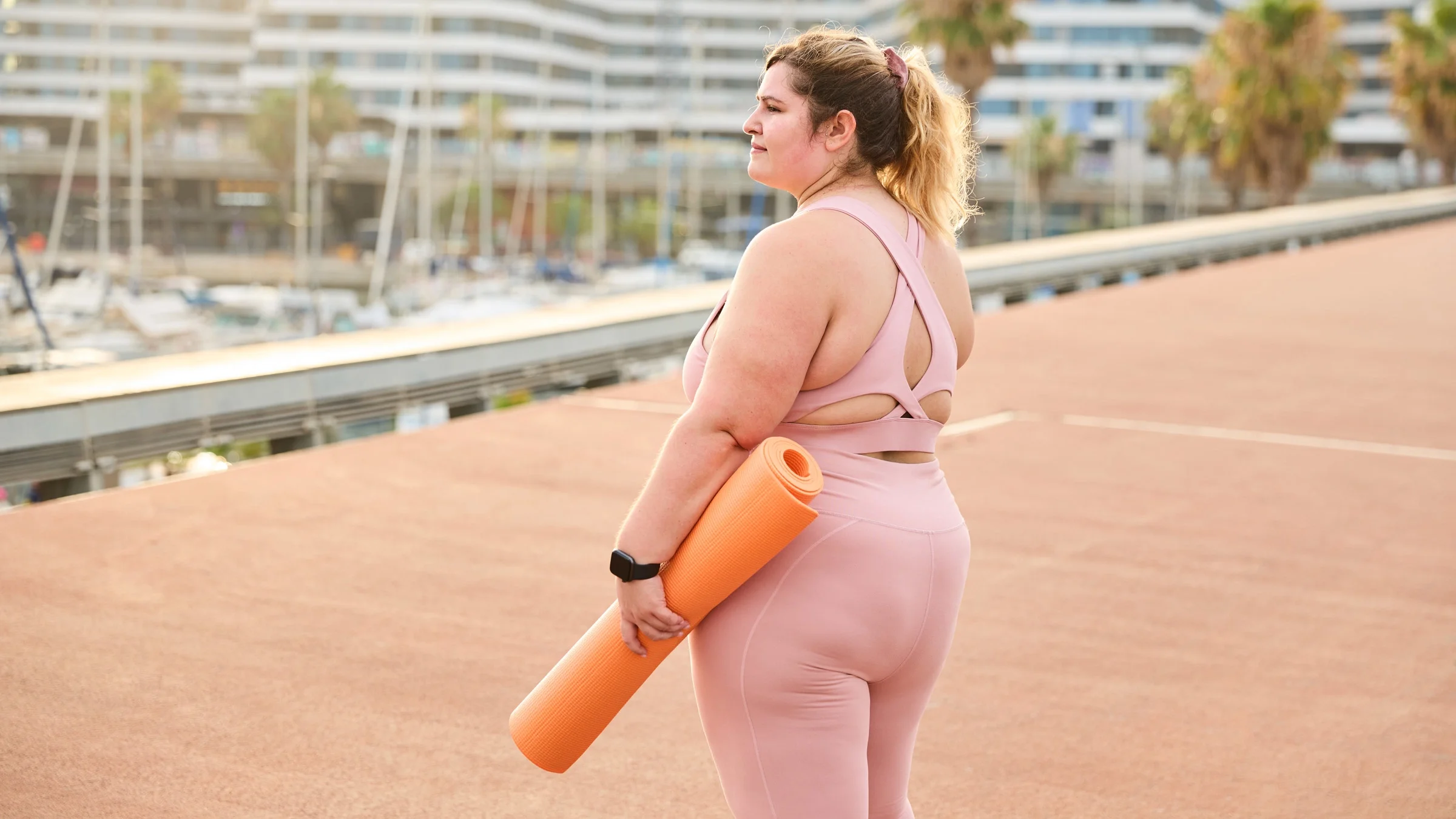 A plus-size person holding a yoga mat. 
