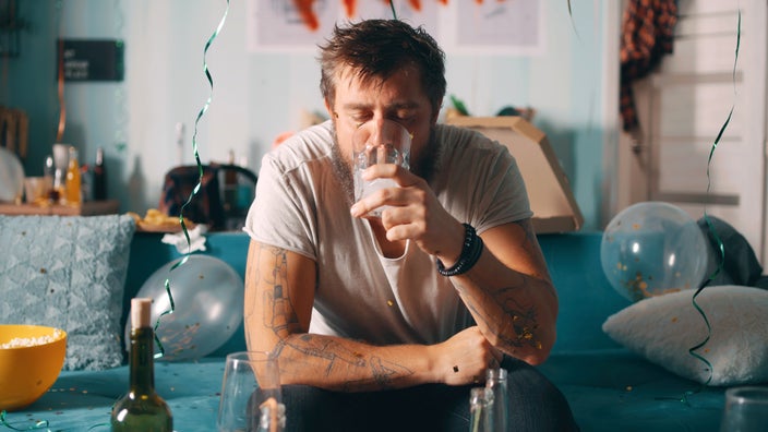 A man drinks a beverage while recovering from a hangover.