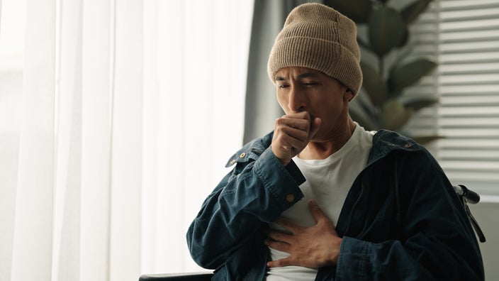A man is coughing and holding his chest in pain.