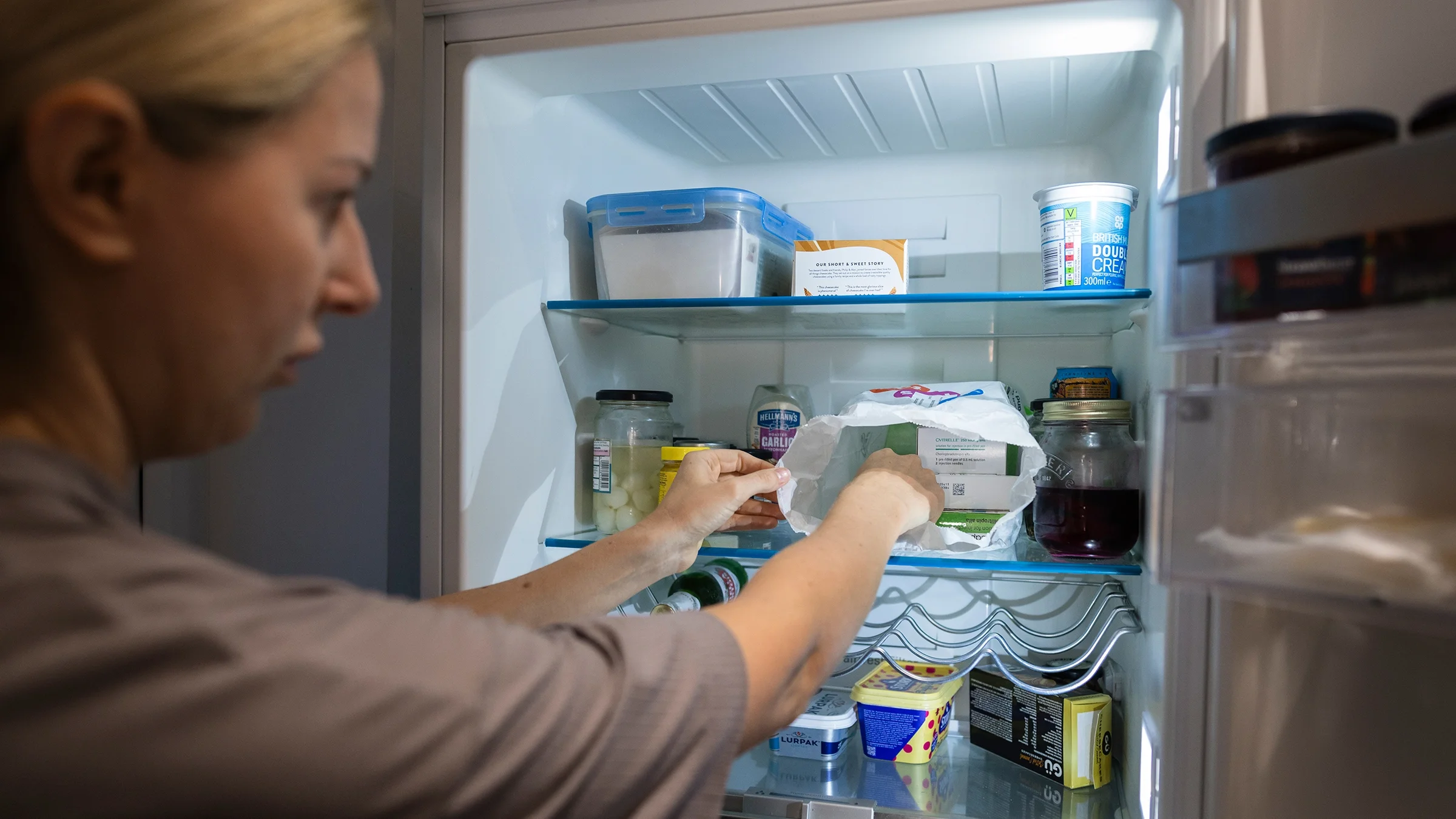 A woman takes her medication out of the refrigerator.