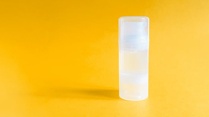 Transparent lube bottle on an orange-yellow background.