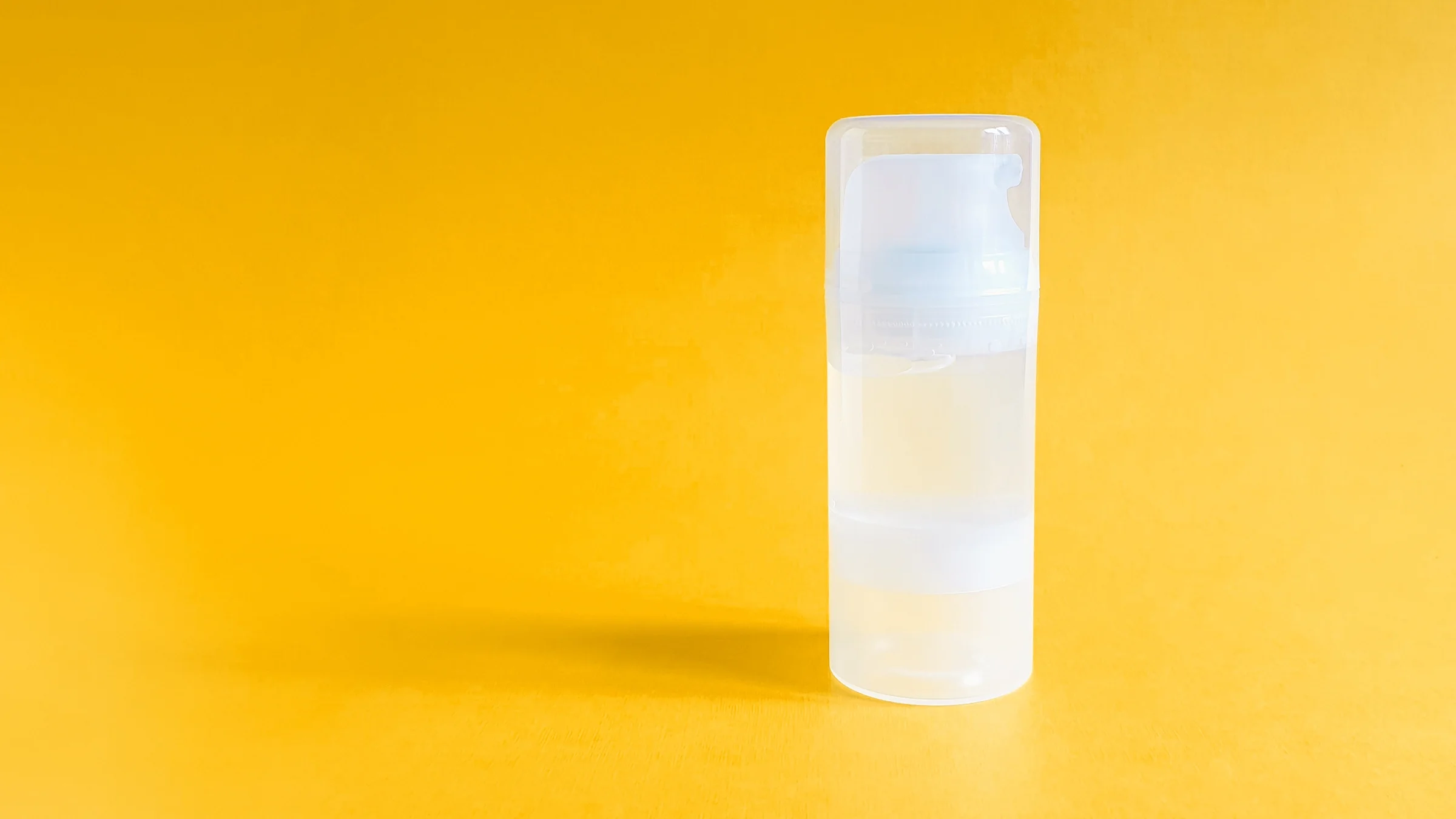 Transparent lube bottle on an orange-yellow background.