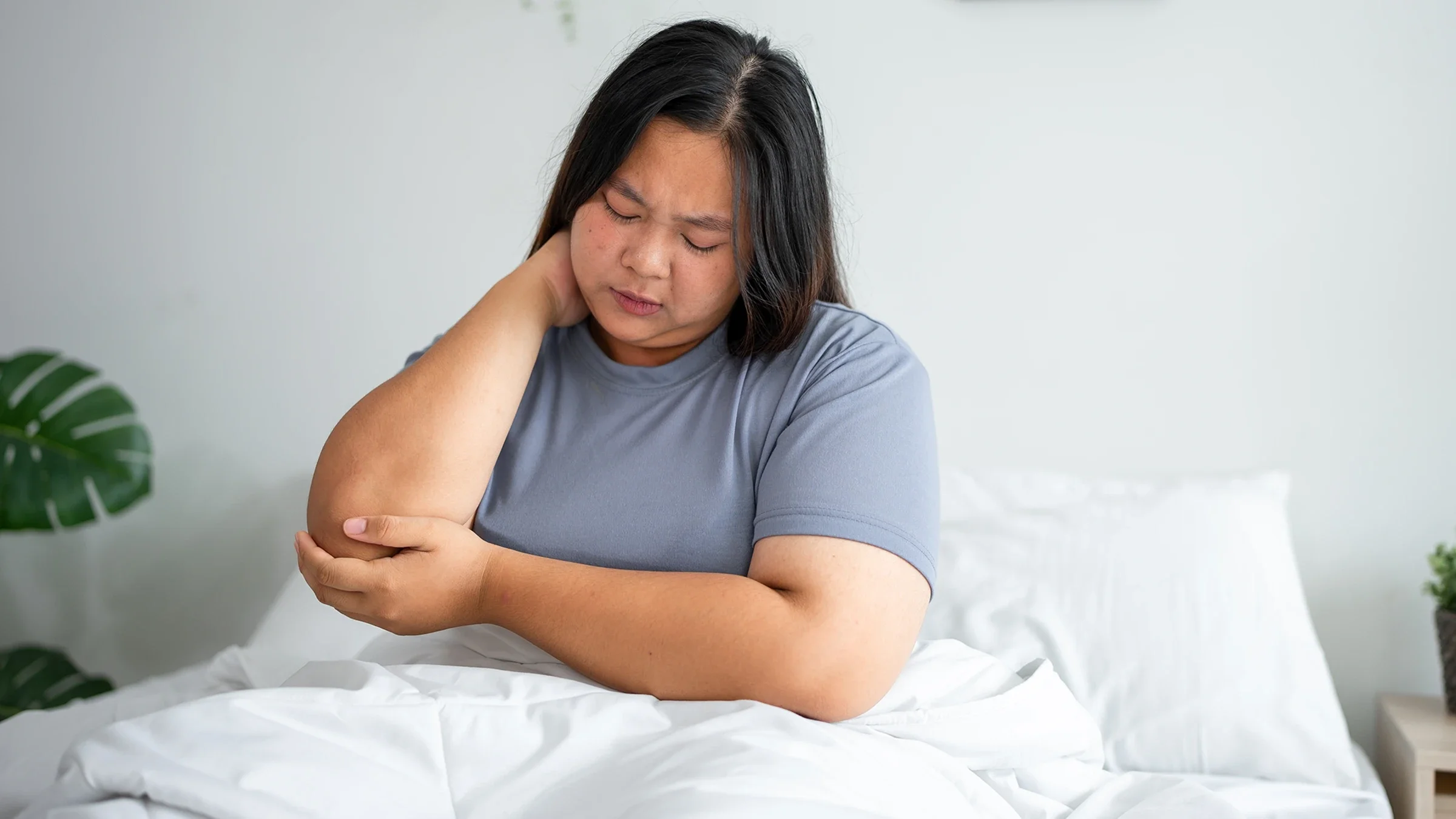 Woman laying in bed with body aches.