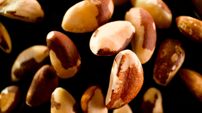 Brazil nuts falling onto black surface