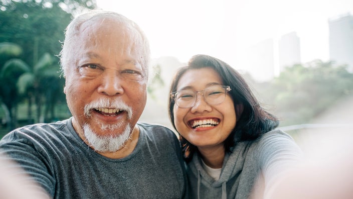 Senior father and daughter taking a selfie outside in the park.