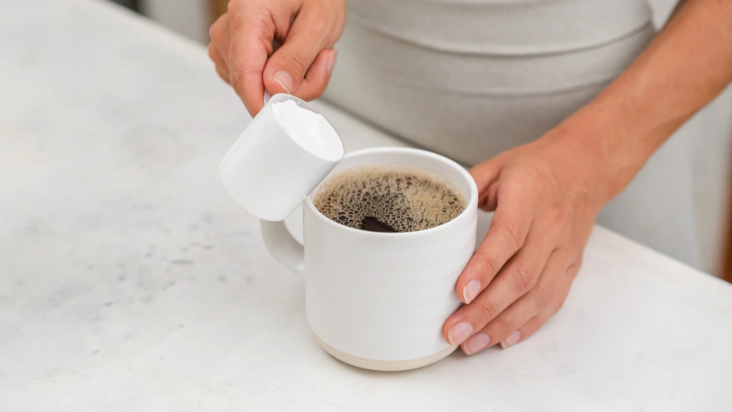 Close-up adding protein powder in a cup of coffee.