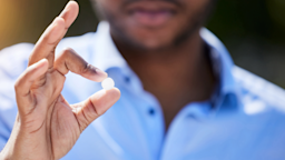 A man holds one single pill between his thumb and forefinger.
PeopleImages/iStock via Getty Images