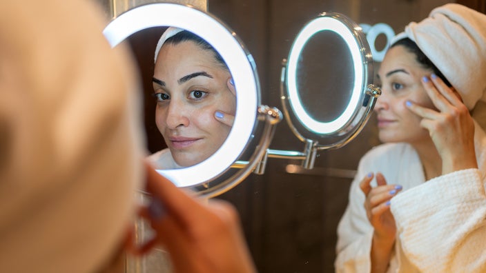 Woman applying face cream after a shower.