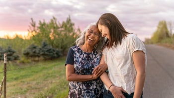 healthy aging: senior mother walking with daughter outside-1329429481
