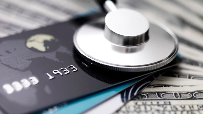 A stethoscope on top of credit card and bills.