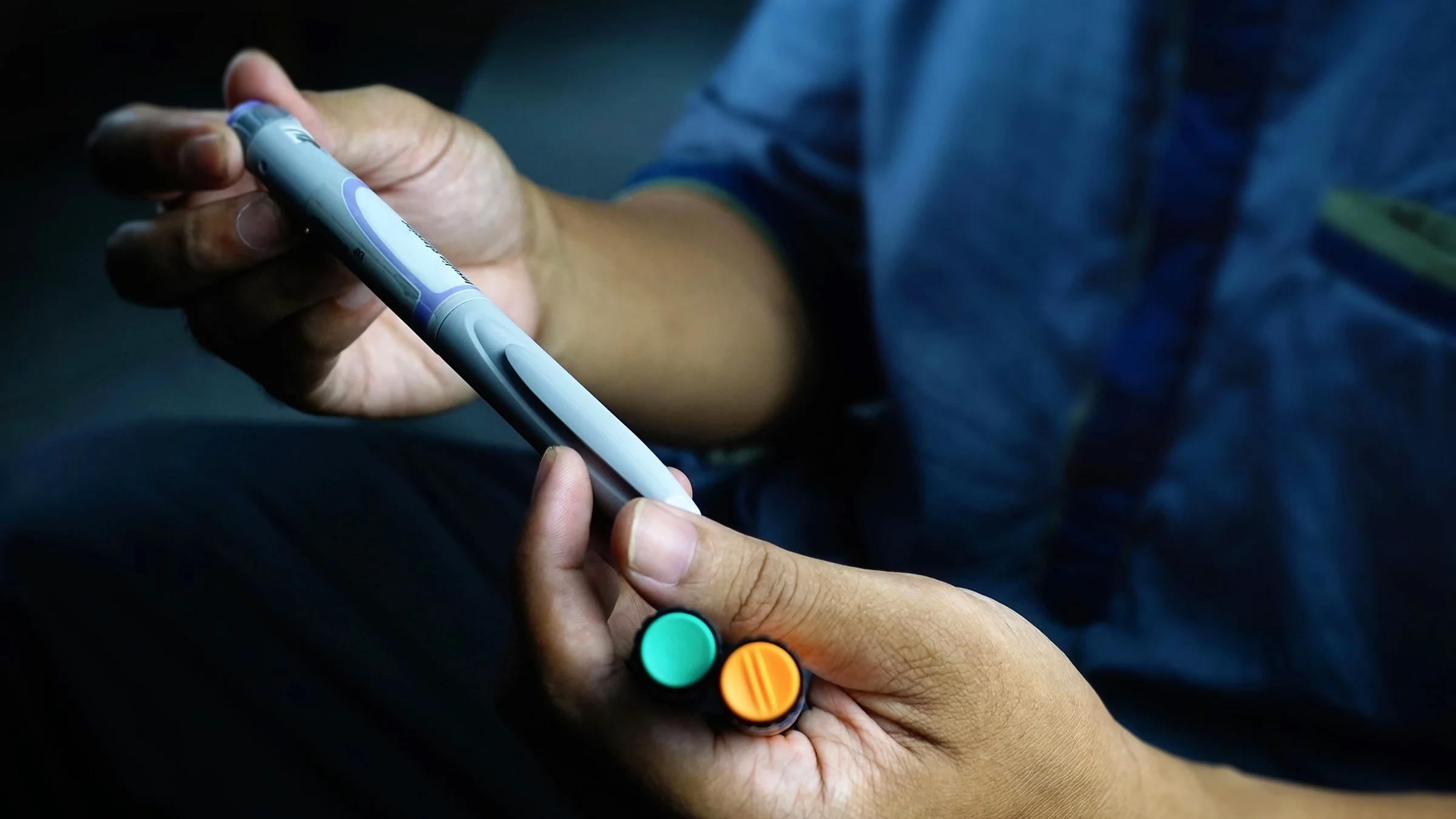 A man is shown holding multiple insulin pens in a close-up.