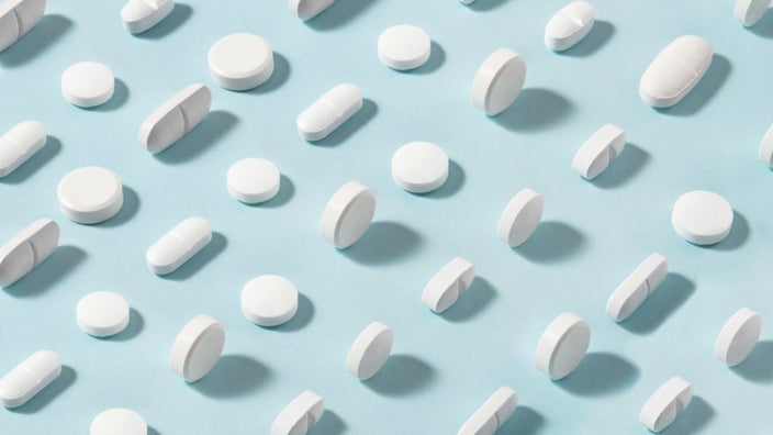 Patter of two types of white pills on a light blue background.