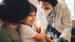 Parent holding young child as they get a shot from their doctor.
jacoblund/iStock via Getty Images
