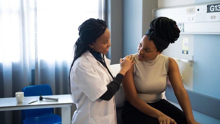 A doctor comforting a young female patient.