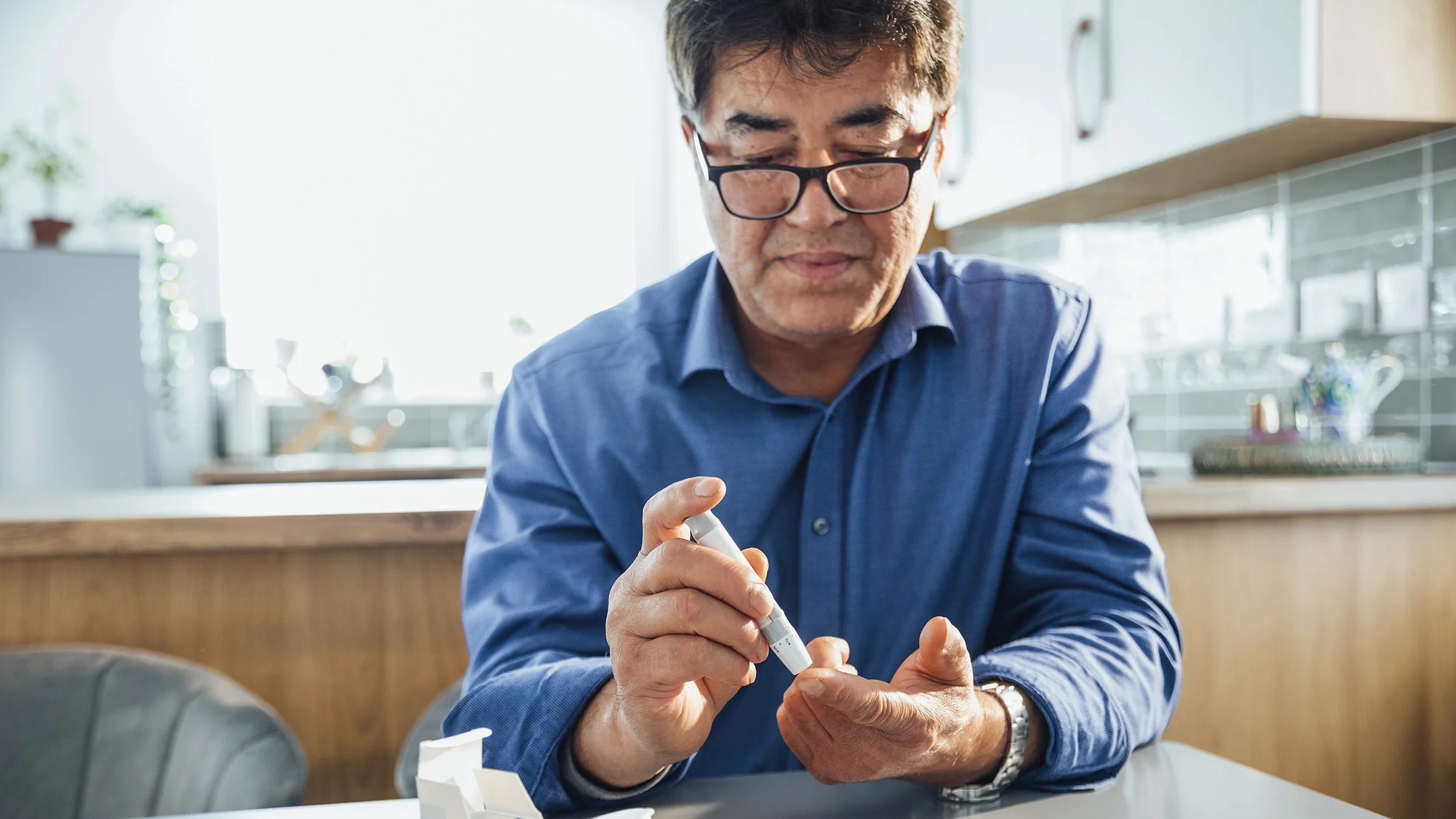 A senior man tests his blood sugar at home.