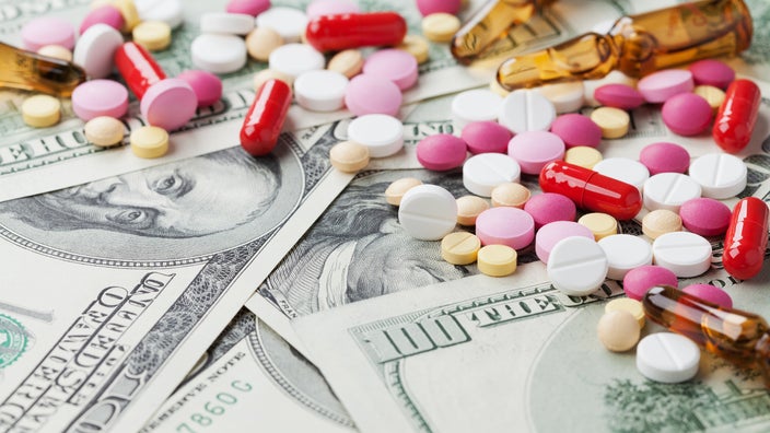 Colorful pills on a pile of hundred dollar bills.
