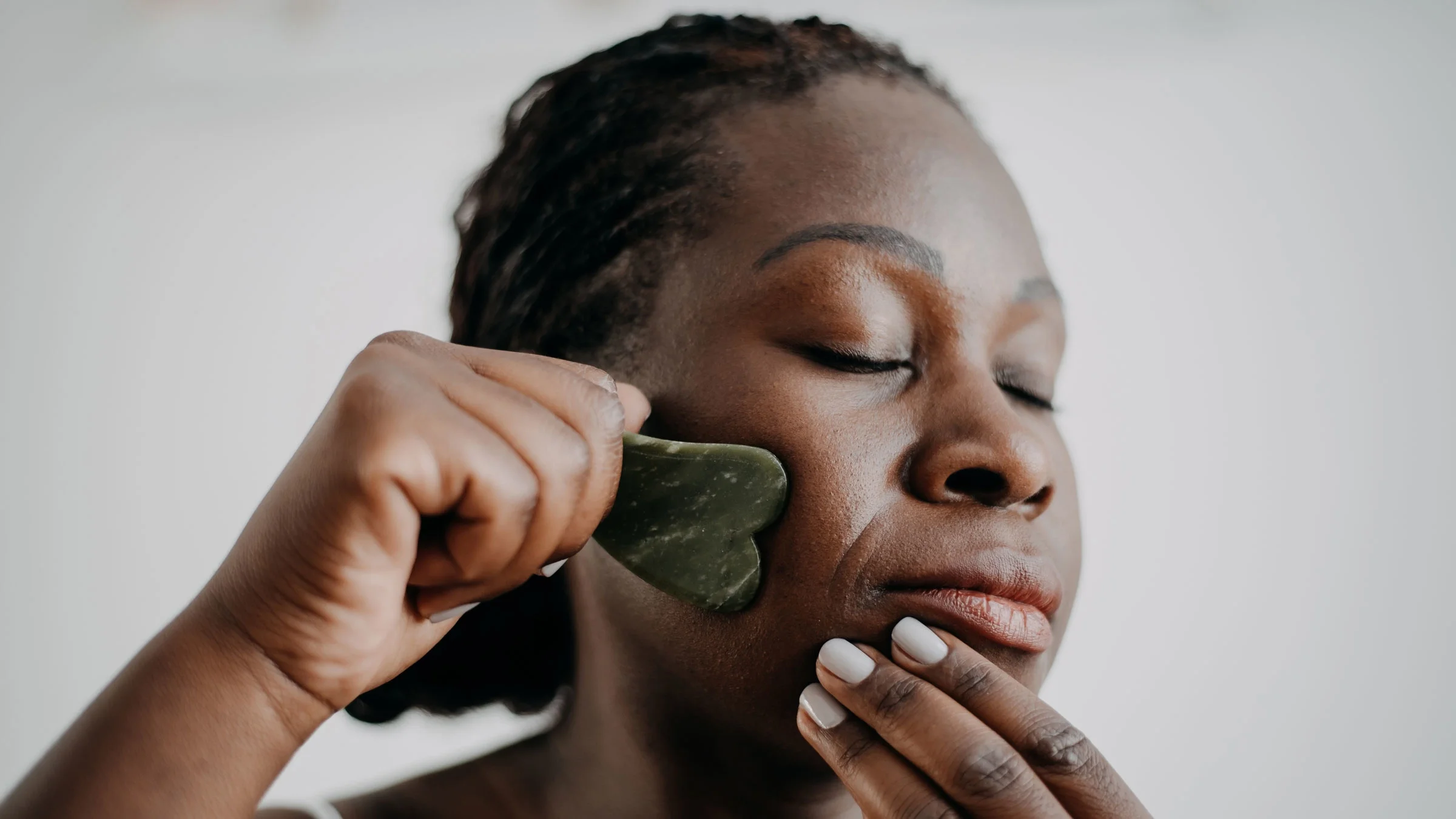 A woman is doing gua sha as part of her skin care routine.