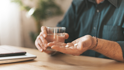 Close-up on a man holding two white pills in the palm of his hand.
Andrii Zastrozhnov/iStock via Getty Images