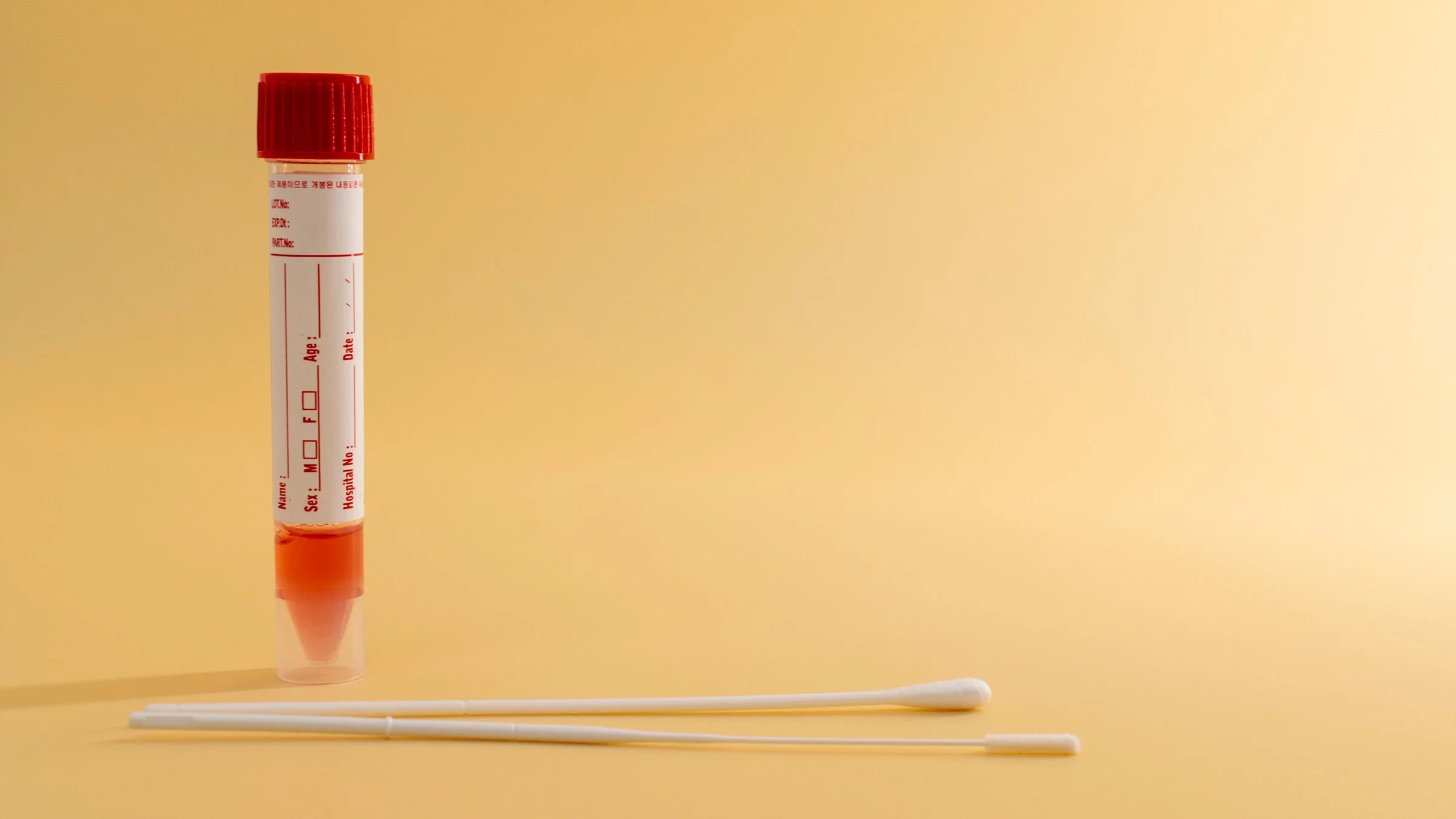 COVID-19 test tube and cotton nasal swabs on a yellow background.