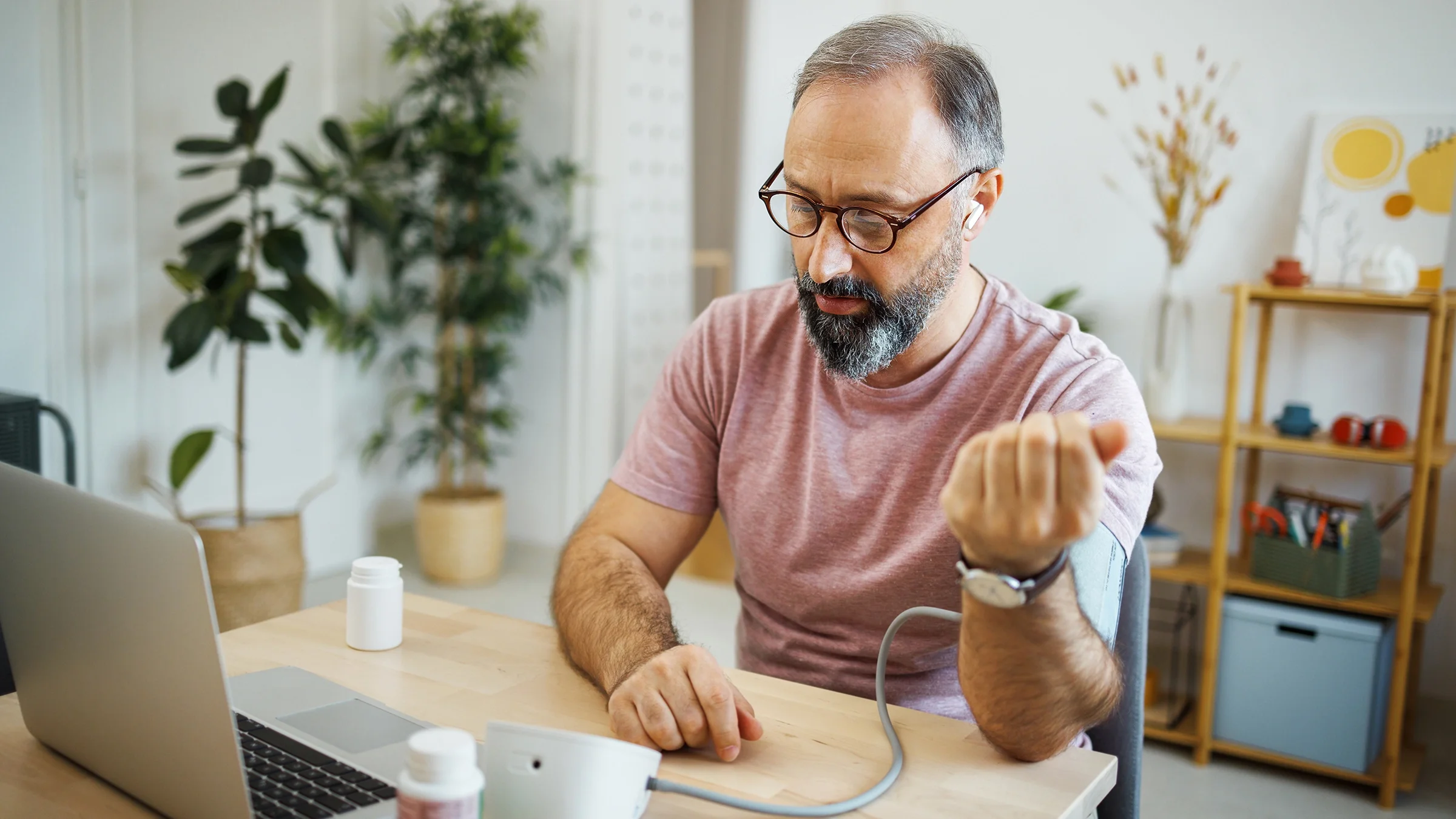 A man checks his blood pressure during a virtual appointment with a healthcare professional. 
