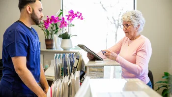 Healthcare-access: woman checking out at doctors office 2206429140
