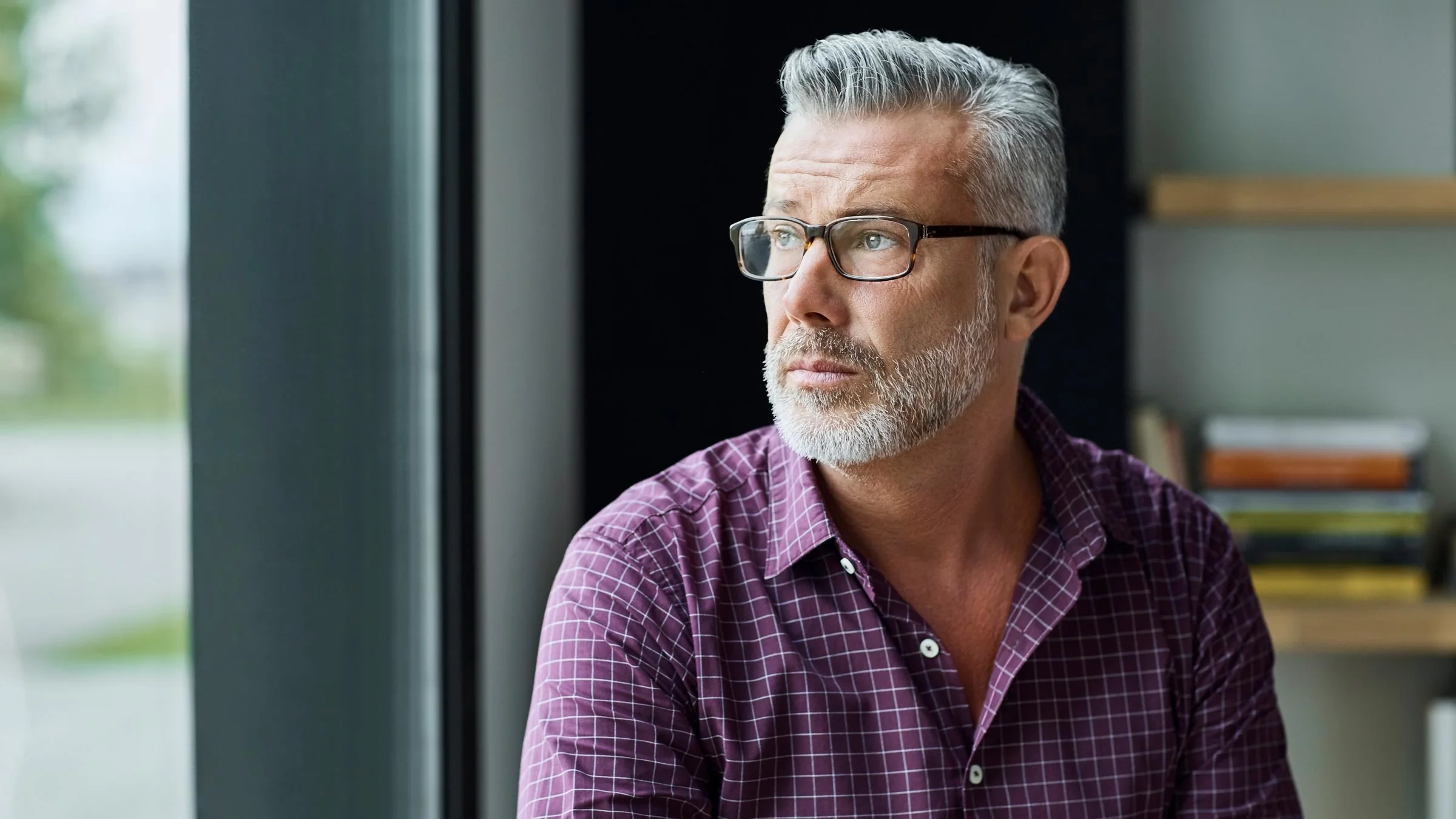 A man stares pensively out the window.