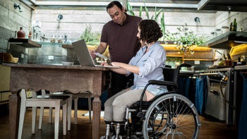 Personal finance: Long-term care insurance: person in wheelchair going through finances w spouse 1313331788