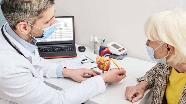 A doctor showing an anatomical heart model to a patient.