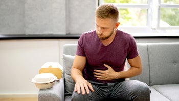 gut health: man bloated after eating take out food 1334047332