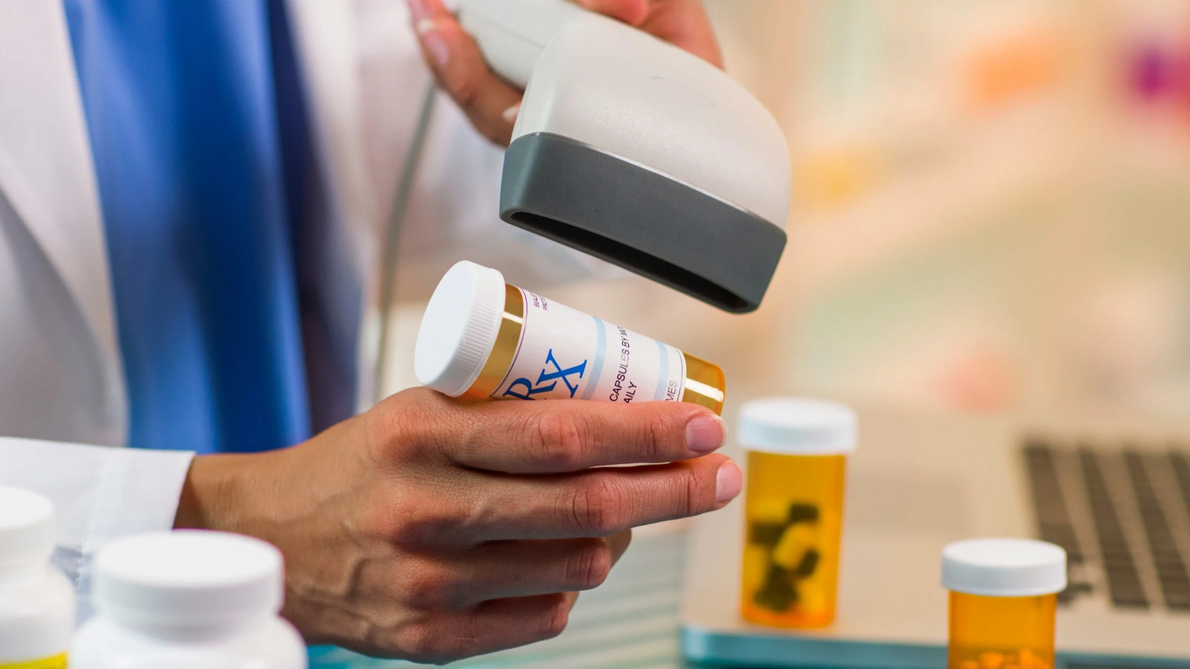 A pharmacy cashier scanning the barcode on a pill bottle.