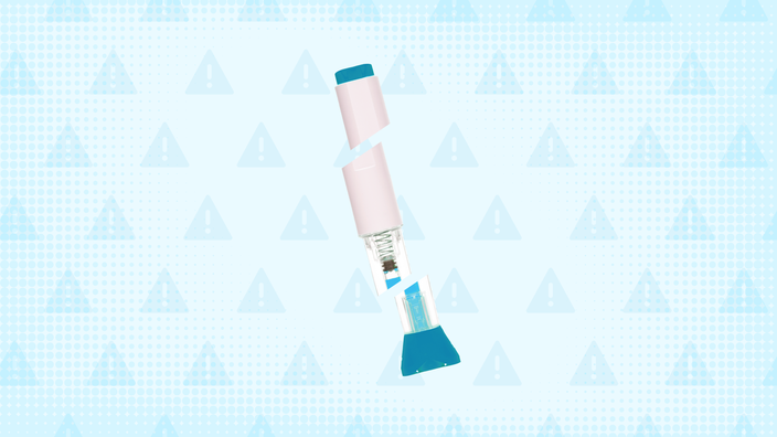 Light-blue background with texture and warning sign pattern. In the center is a blue-and-white autoinjector pen cut into thirds. 