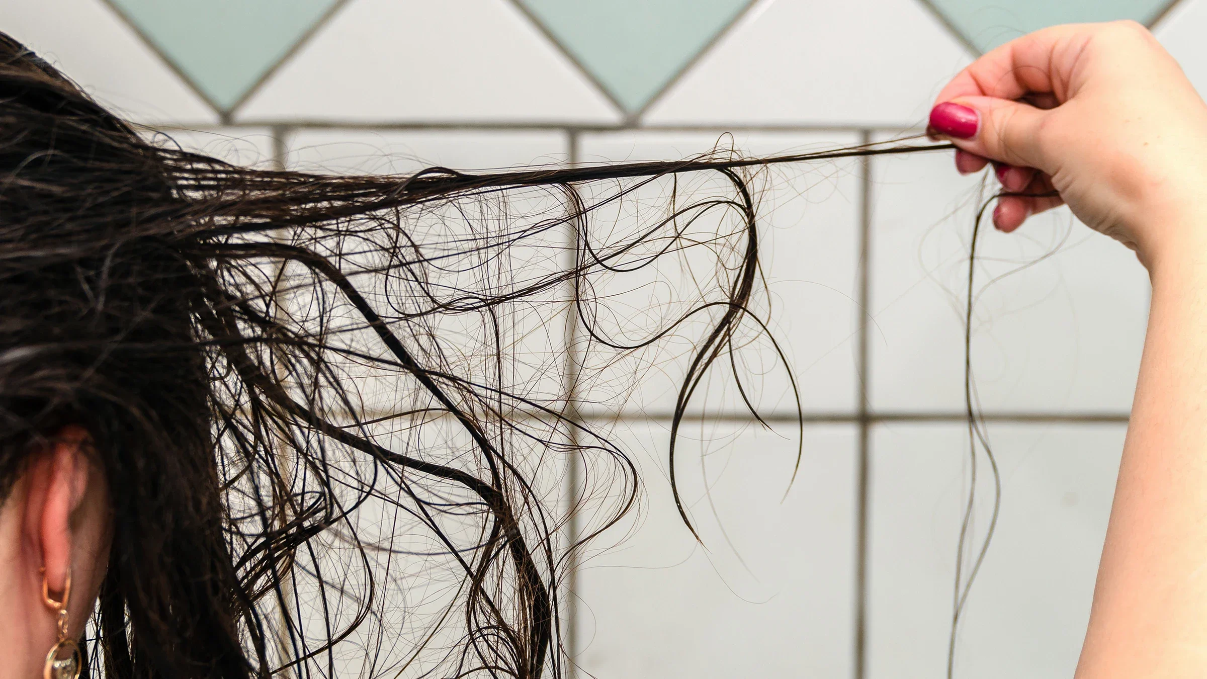 A woman pulls loose strands of hair while in the shower.
Sergey05/iStock via Getty Images Plus