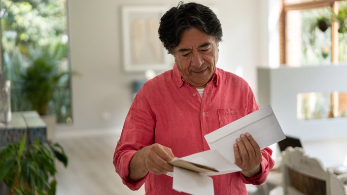Senior man holding envelopes.