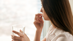 A woman takes a pill while holding a glass of water.
fizkes/iStock + via Getty Images Plus