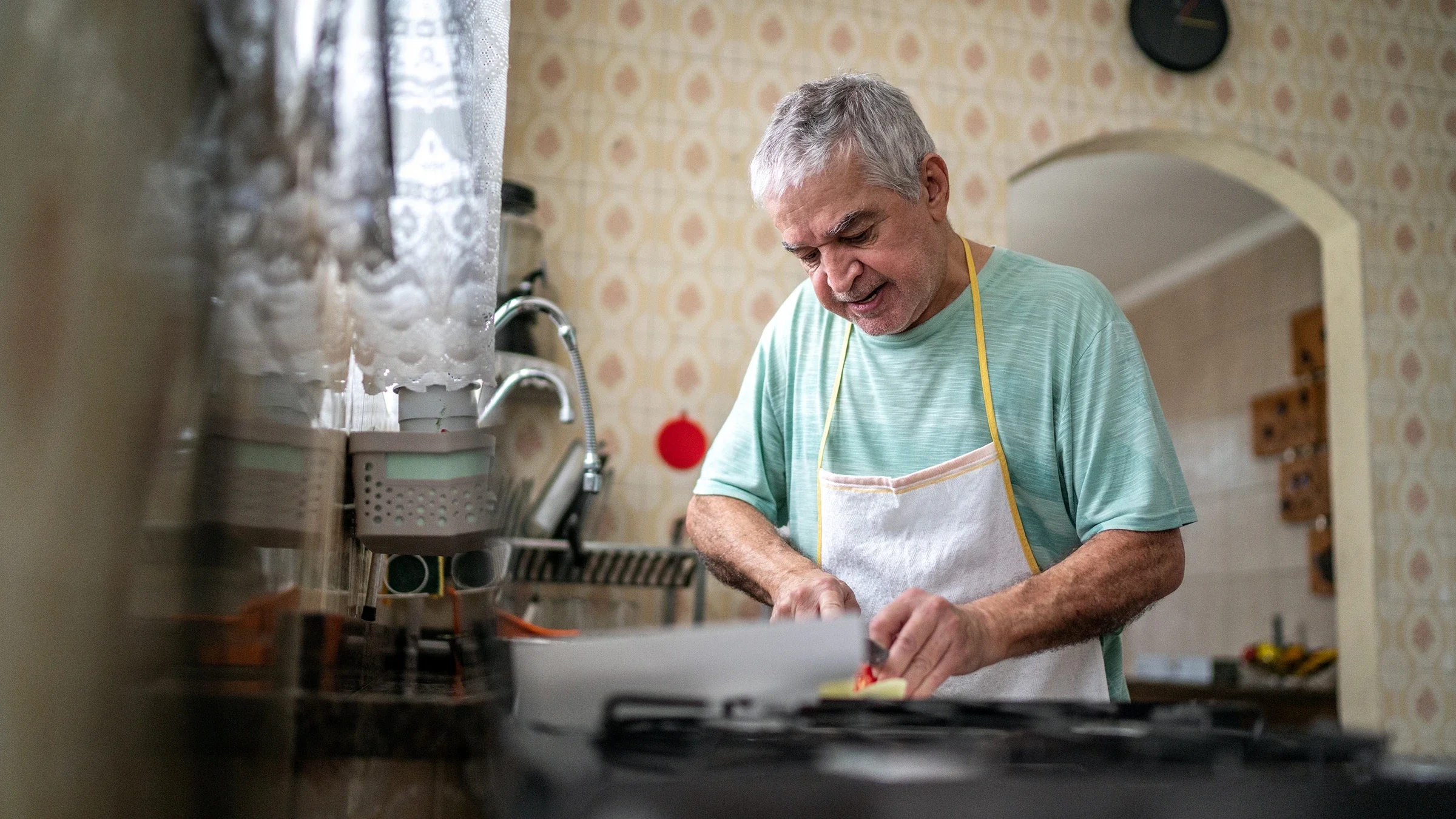 A man cuts vegetables in his kitchen. Certain vegetables and fruits can help prevent prostate cancer, according to research.