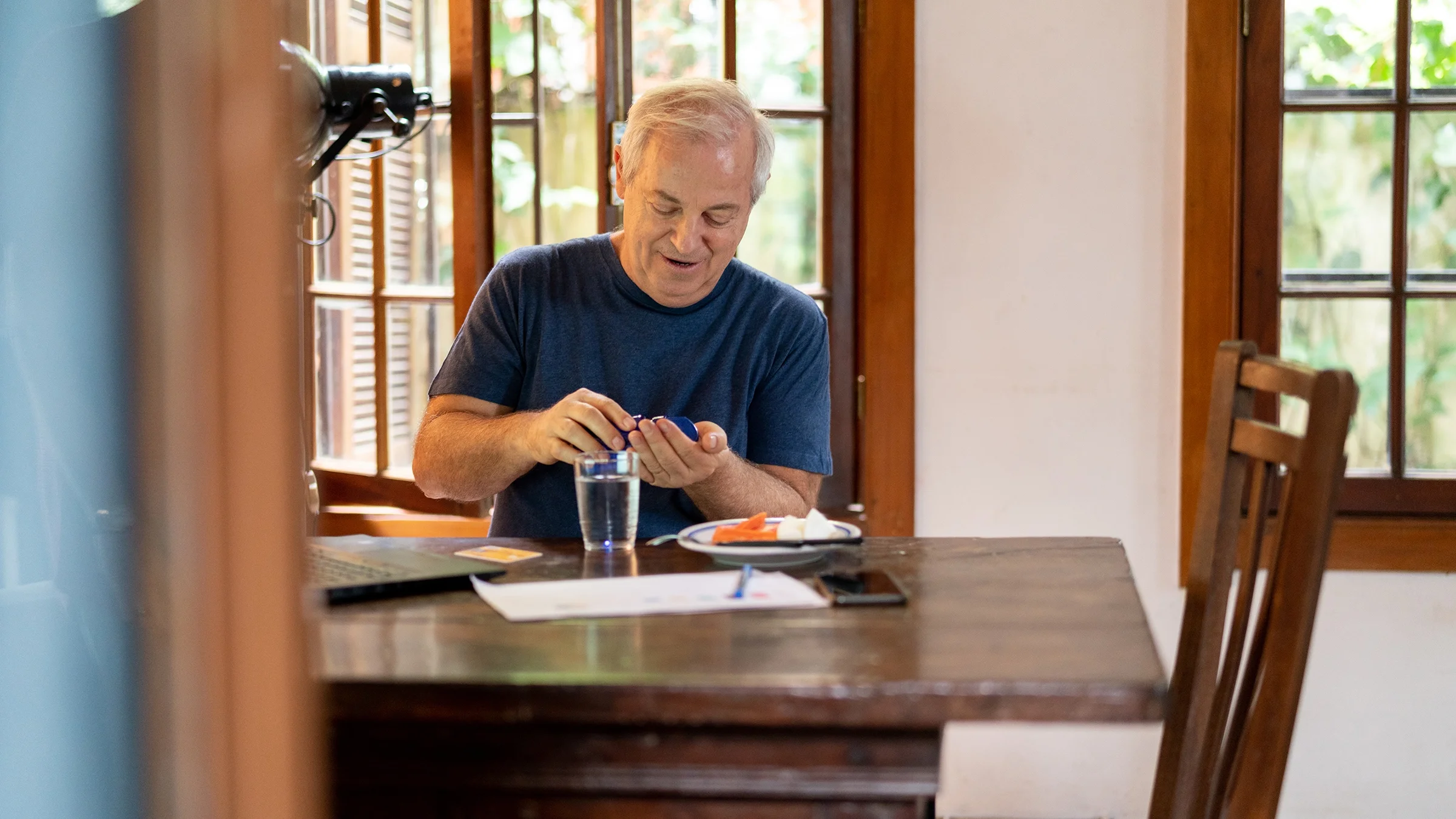 enior man taking his pills at the dining table. The view is from the doorway.