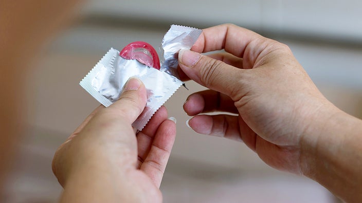Hands tearing and holding a condom