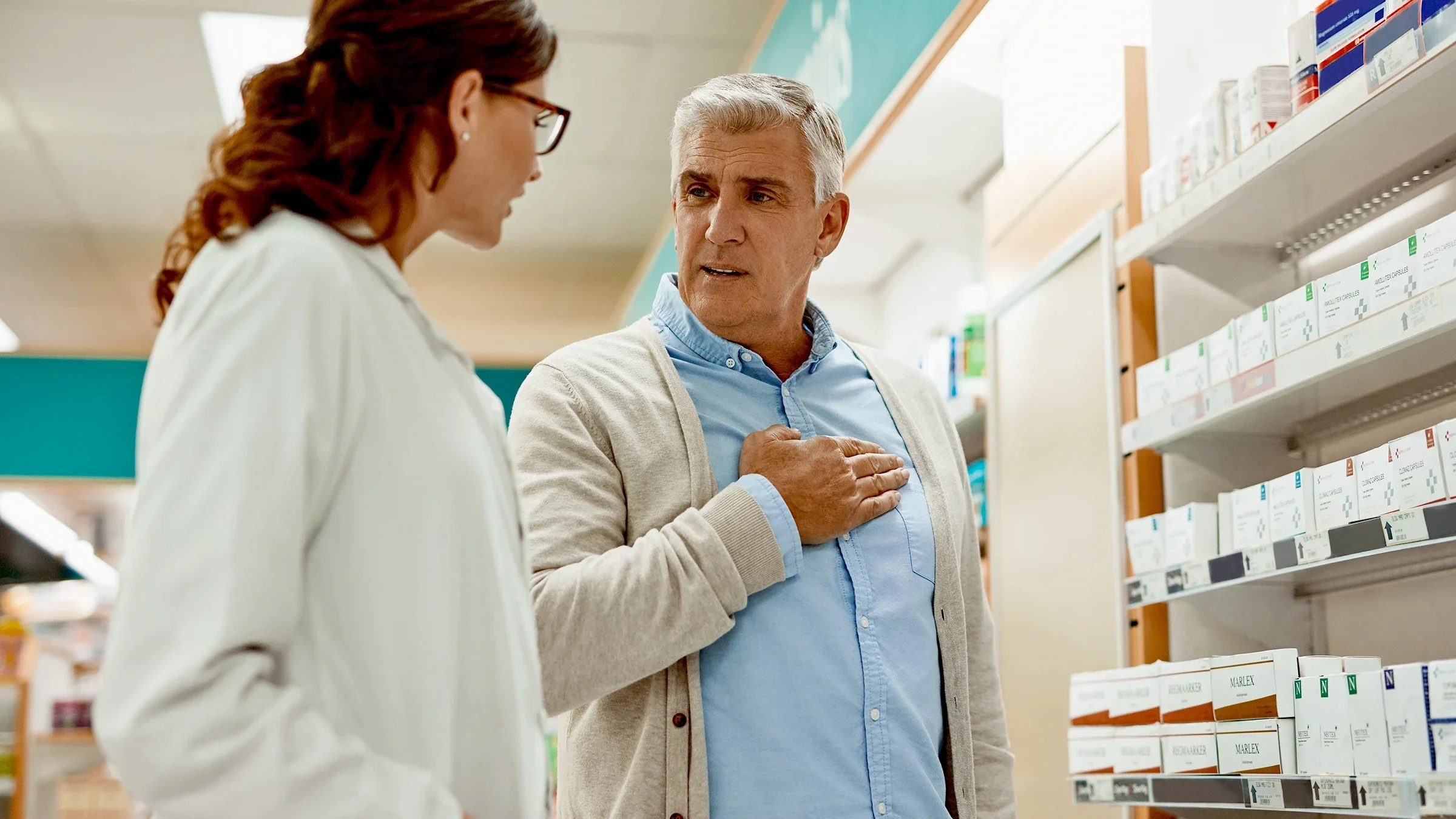 Man consulting with pharmacist in medication aisle.
LumiNola/E+ via Getty Images