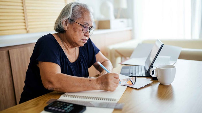 A senior woman calculating expenses and bills in her home.
