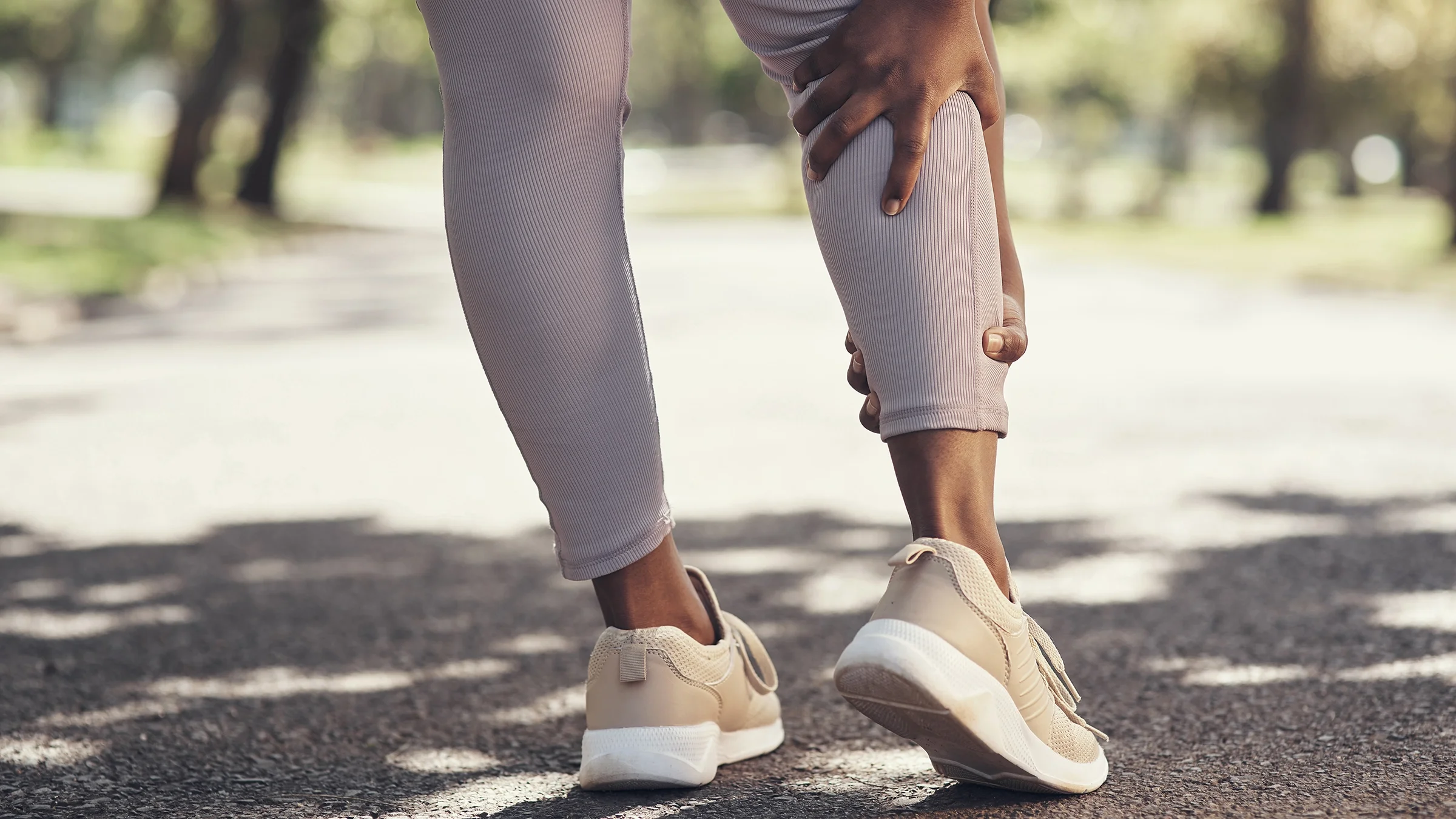Close-up of a runner's calf muscle as they take a break to rub a cramp.