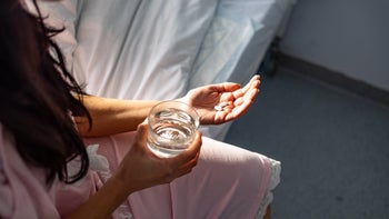 menstrual pain: woman taking pill in bed 1487443041