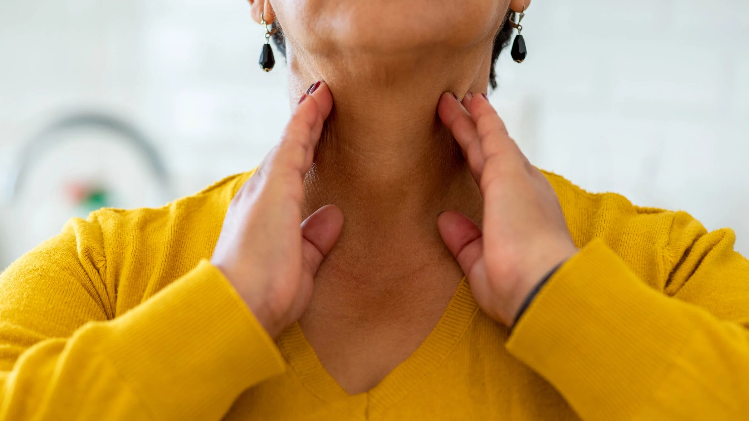 An adult has their hands on their throat glands.